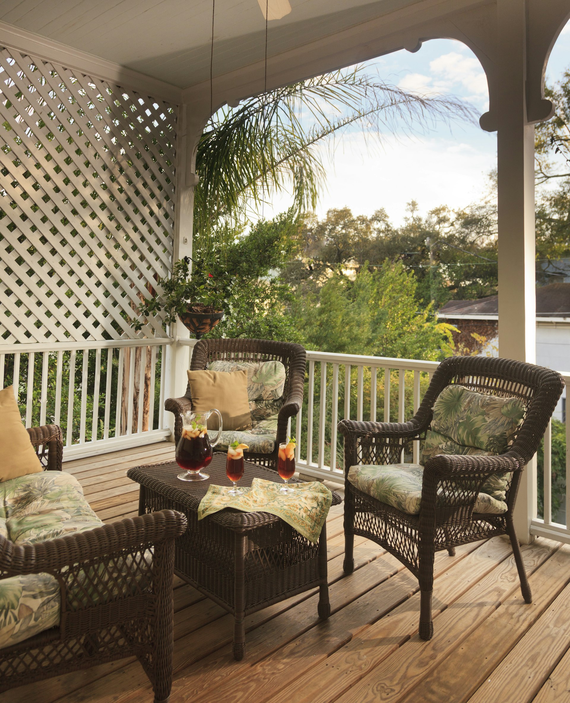 A pair of wicker chairs and a table with iced tea sit on a back porch in the early evening in Savannah Ge