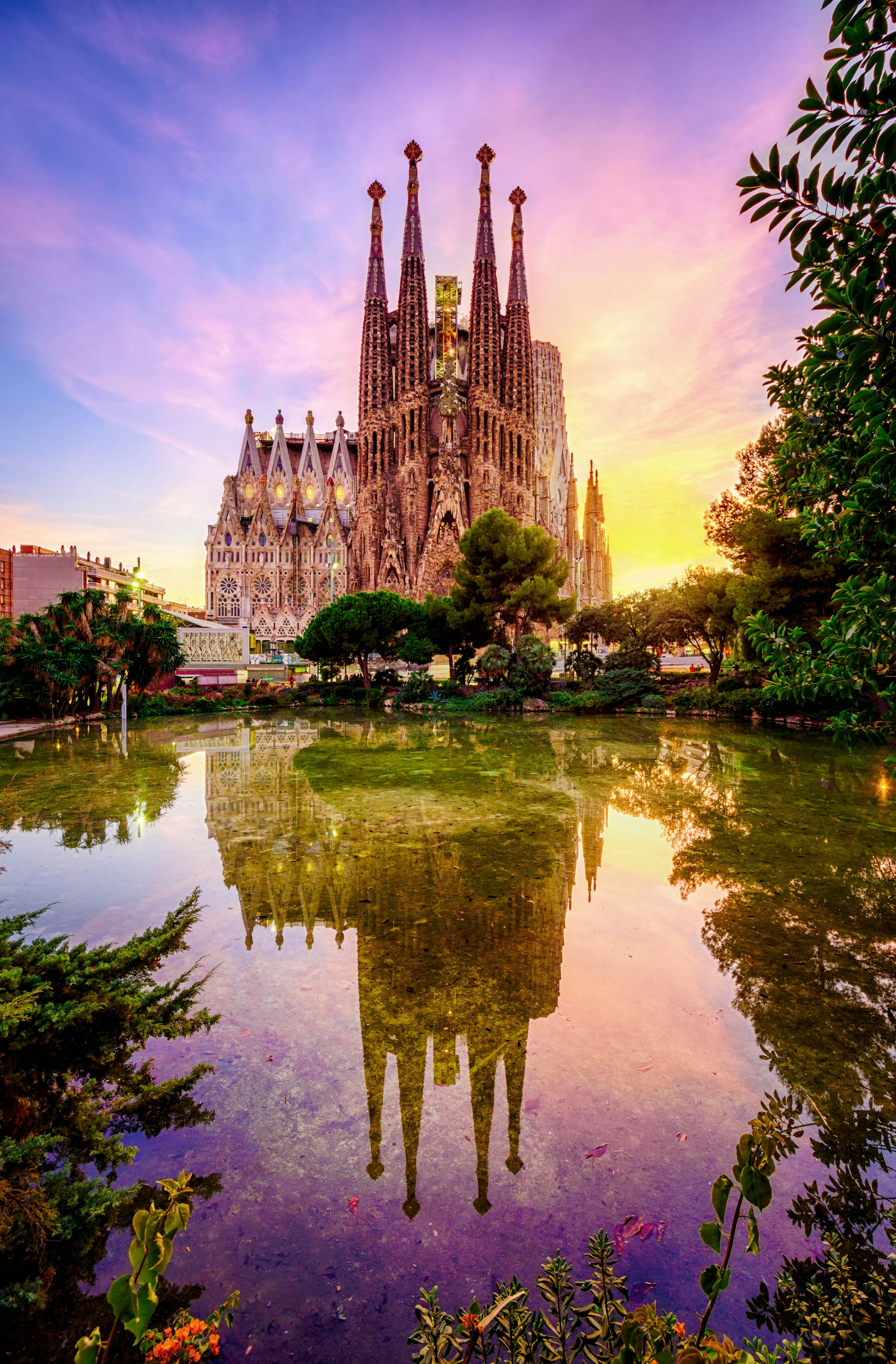La Sagrada Familia at sunset reflected in a garden pond in Plaza Gaudi in Barcelona, Spain