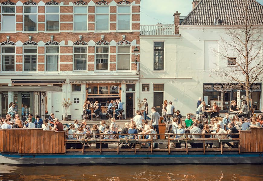 People eating and talking on riverboat cafe on the Amsterdam canal, the Netherlands