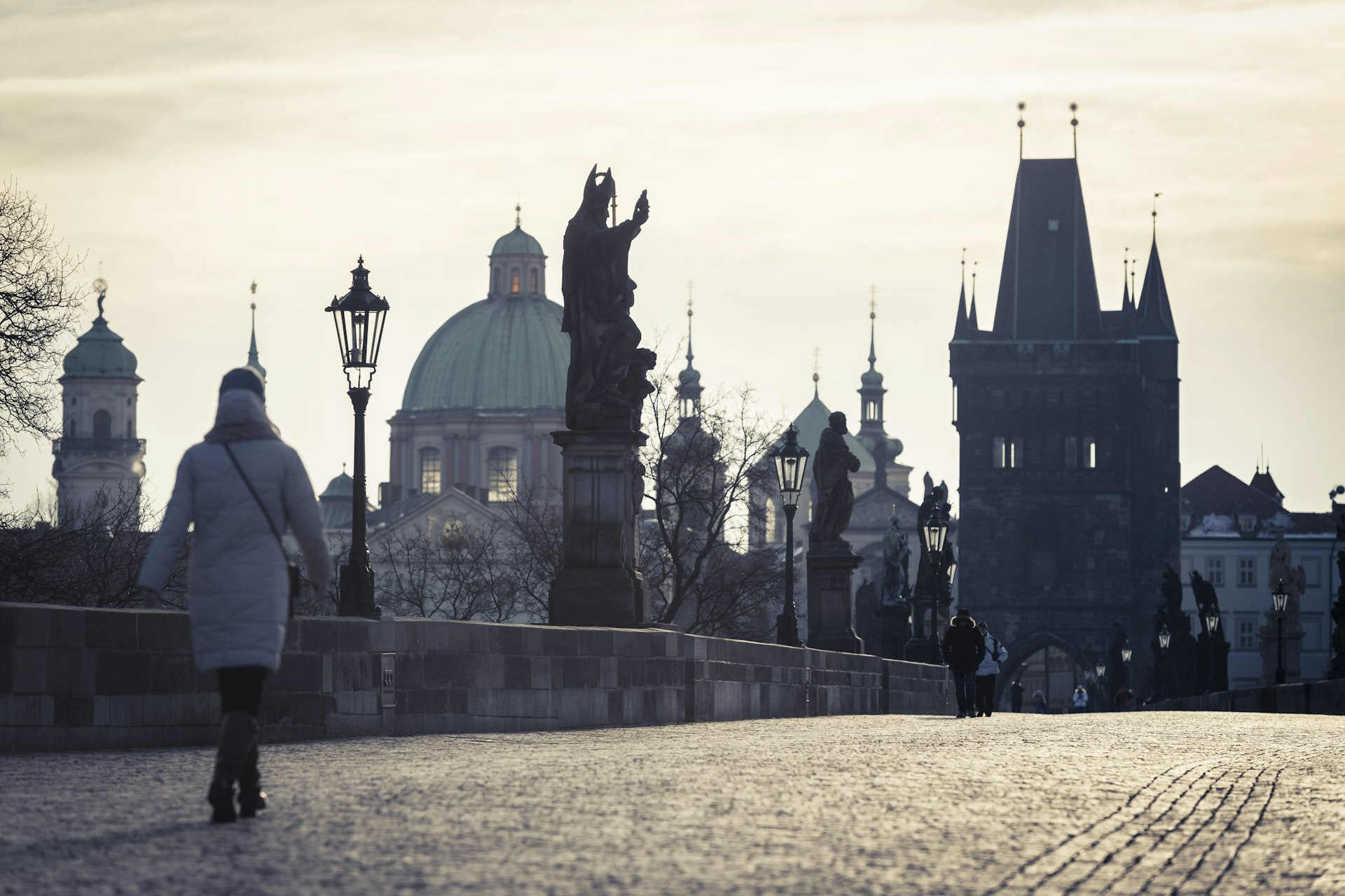 One person walks across the Charles Bridge in Prague on a cold January day