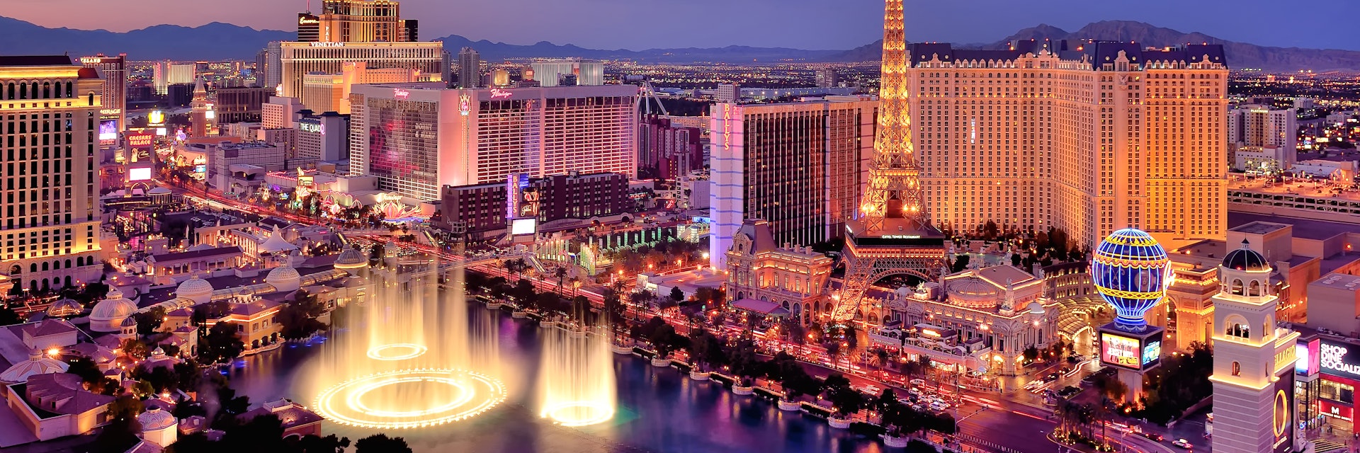 The Las Vegas strip with the fountains of the Bellagio leaping into the air photographed at dusk. 