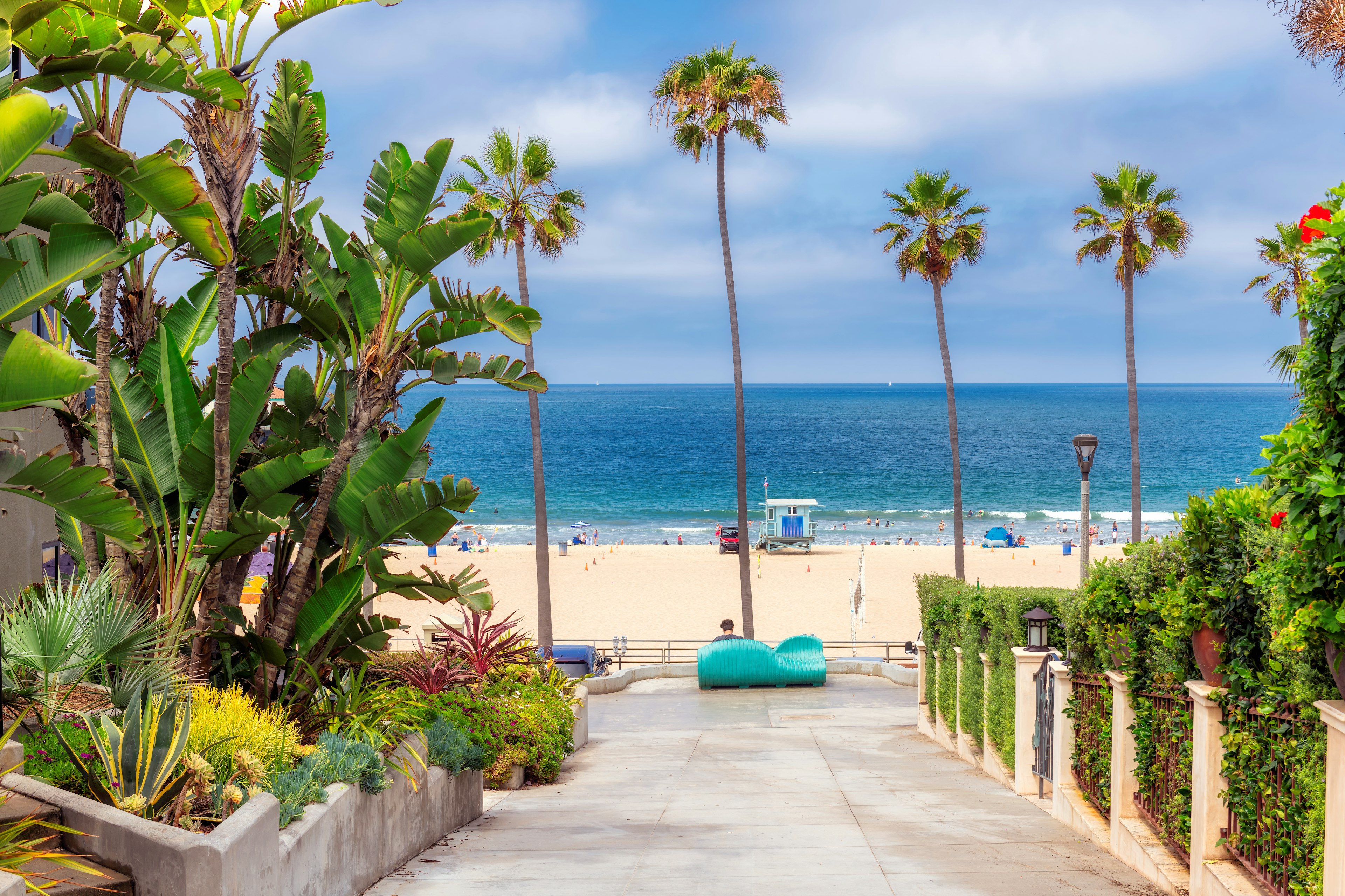 A path leads down to a palm-lined sandy beach with lifeguard huts and lots of facilities