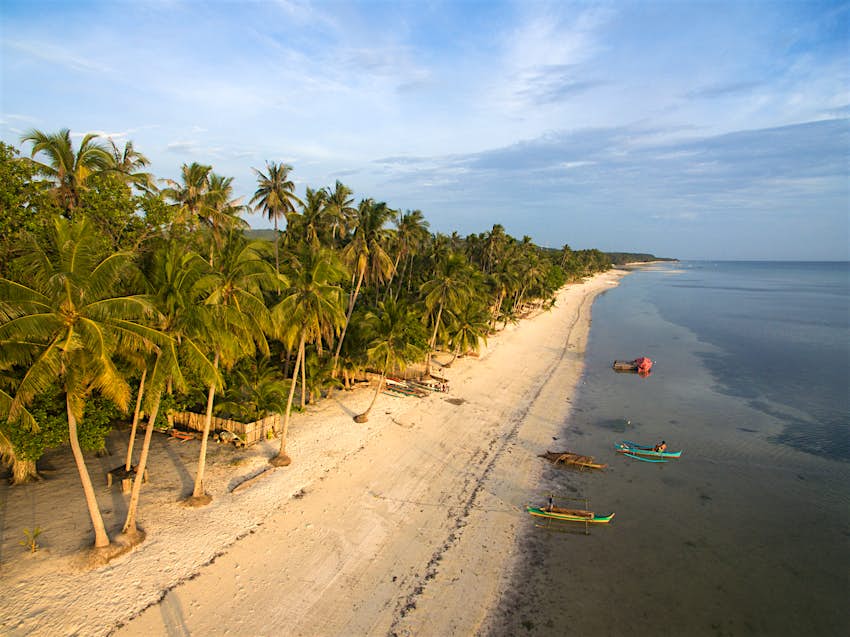 Paliton beach, Siquijor Island. An aerial view of palm-backed Paliton Beach on Siquijor Island. The beach has white sands and is lapped by shallow blue waters.