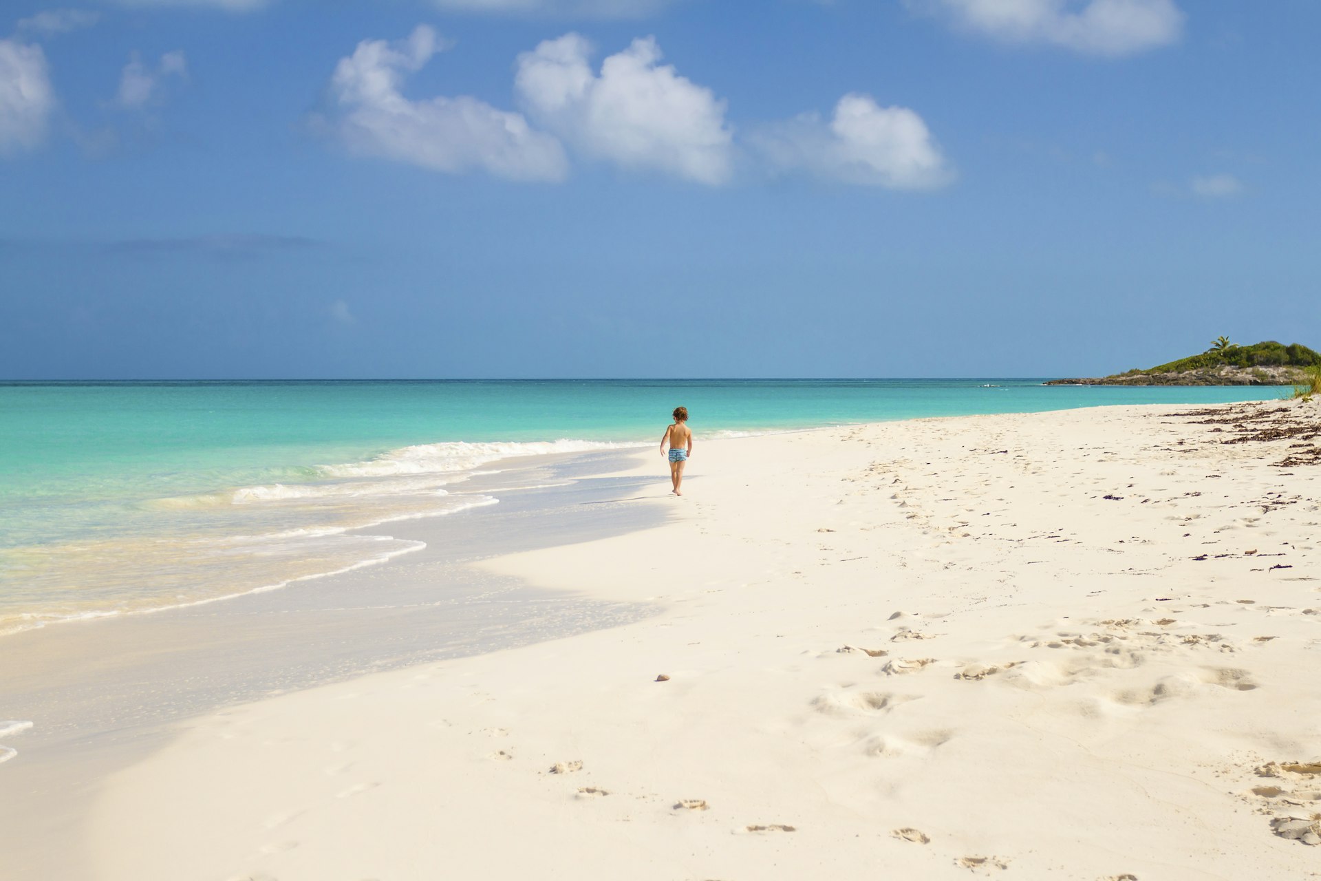 A small child running along the Tropic of Cancer Beach in the Bahamas