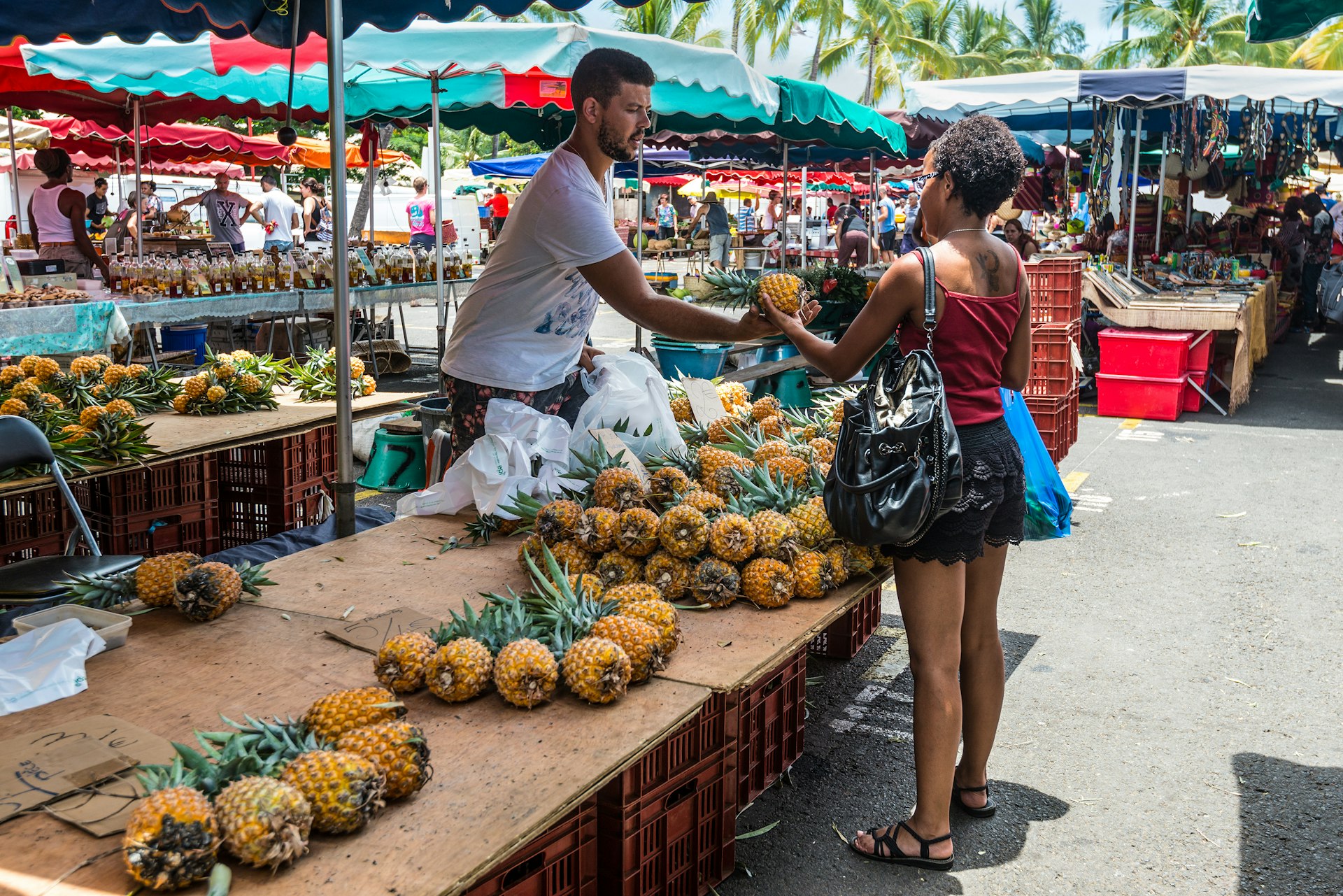En kvinna köper en ananas av en handlare på en utomhusmarknad