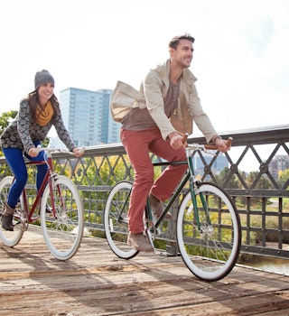 Young couple with urban bicycle in city park in Autumn.