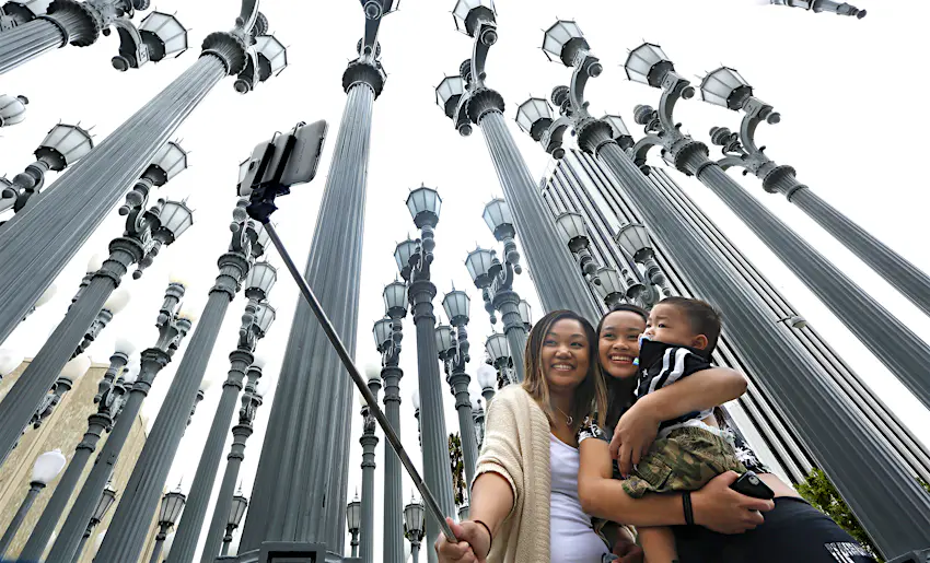 LACMA is one of the best museums in Los Angeles Three people taking a selfie in front of the Urban Light installation at the Los Angeles County Museum of Art