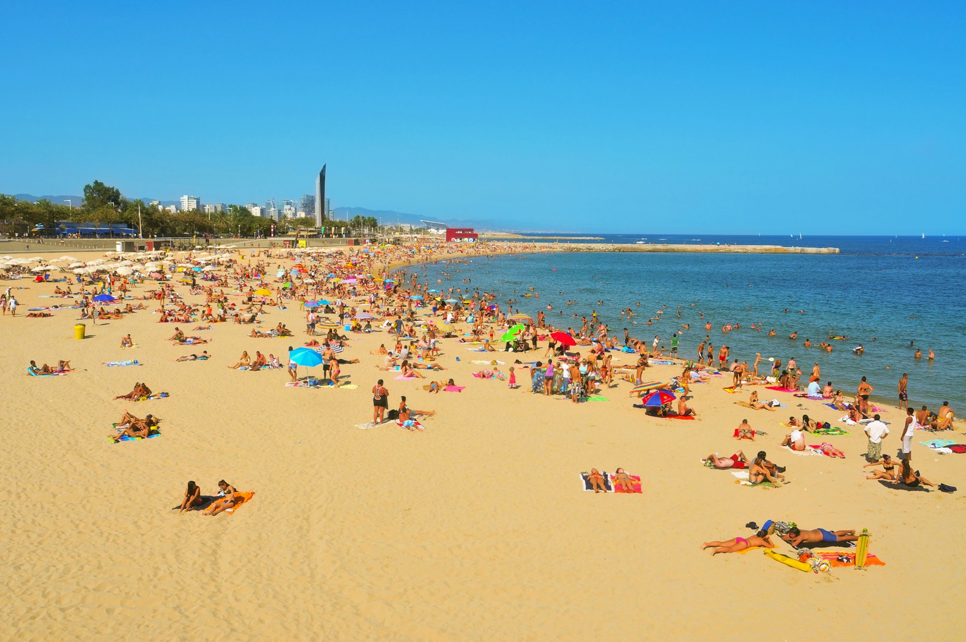 Sunbathers spread out across Nova Icària Beach in Barcelona 