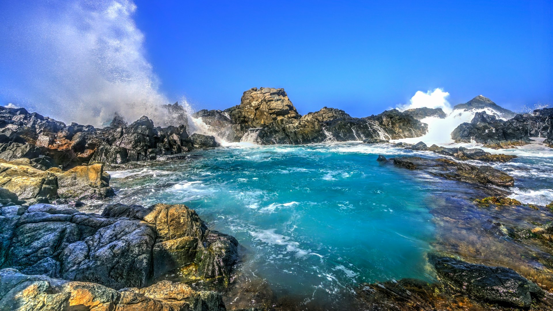 Waves crash on natural rock at the Natural Pool in Aruba 