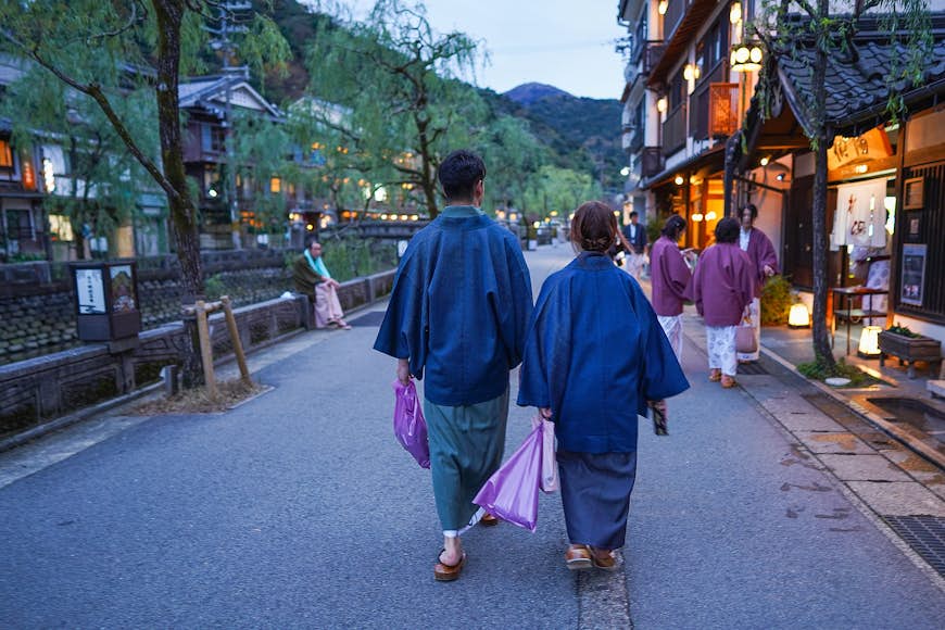  Japanese couple wearing yukata and walking outside a Kinosaki Onsen