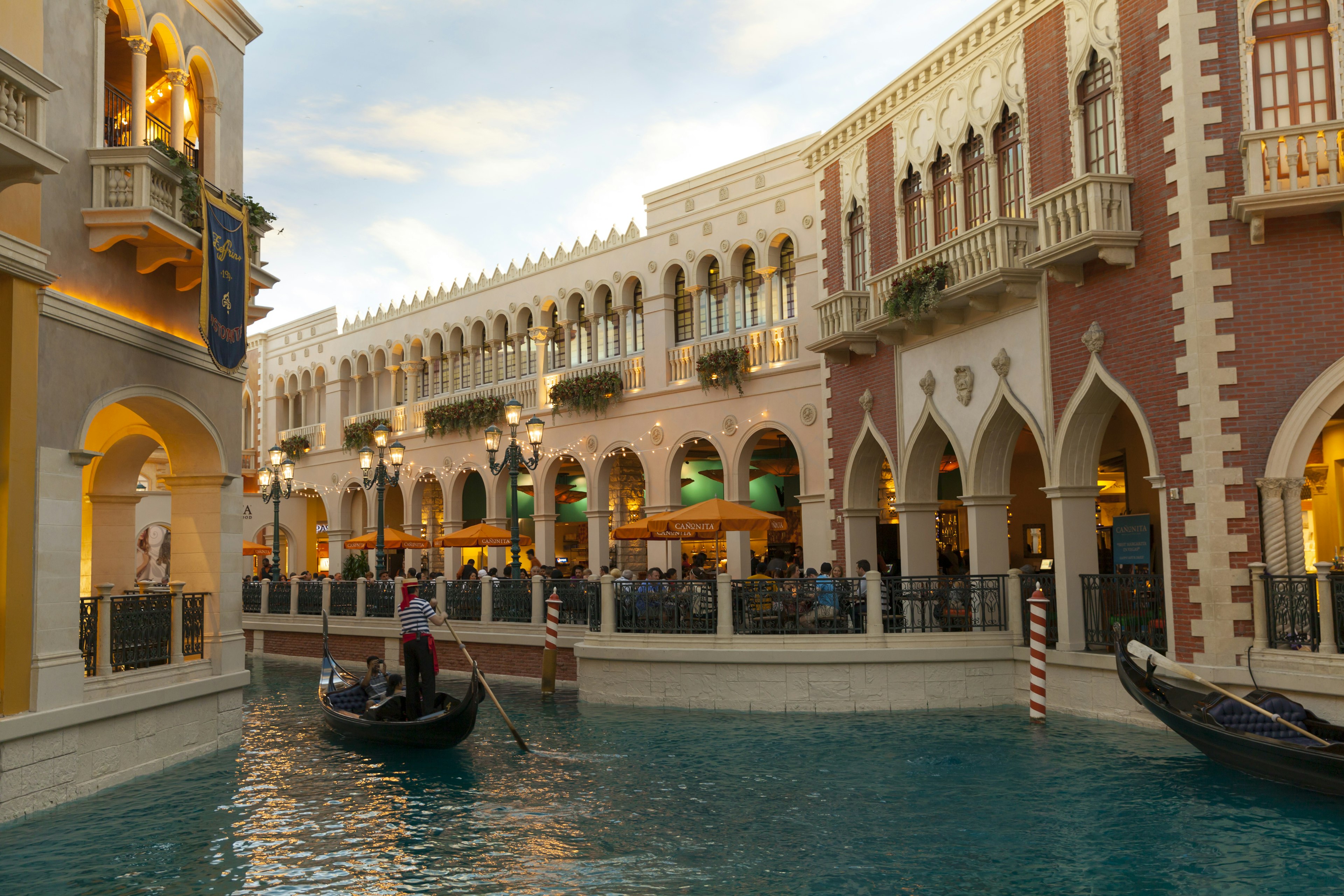 An indoor river with a man on a gondola, with shops flanking each side