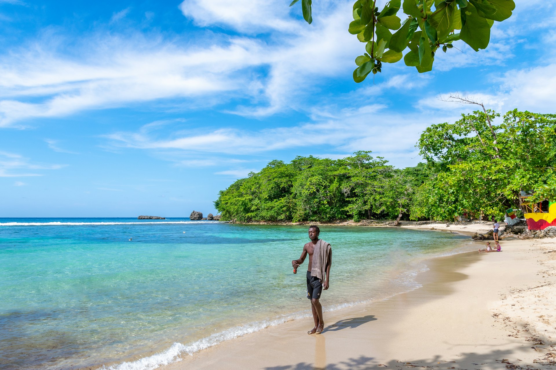 Man walking along Winifred Beach on a sunny day