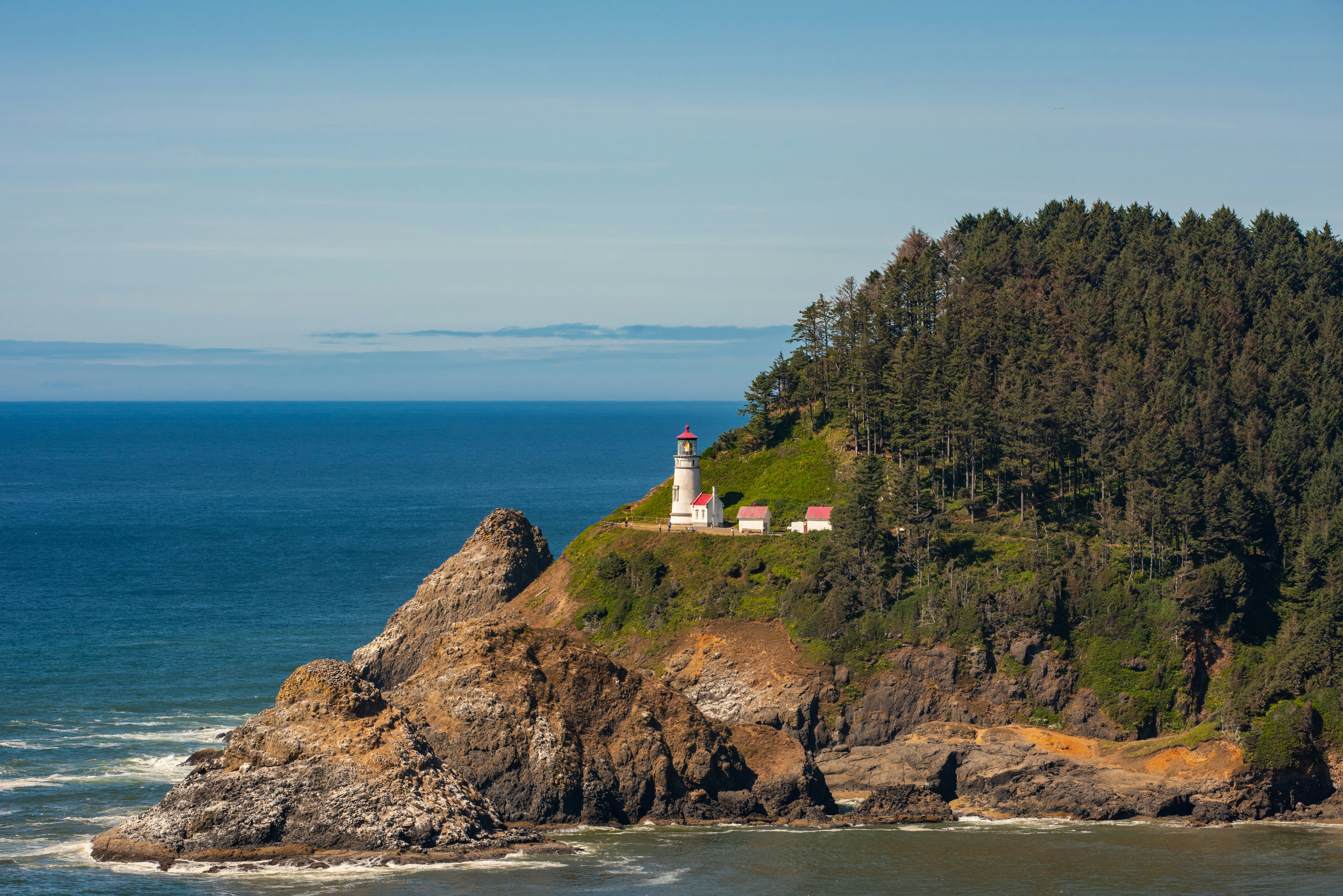 A lighthouse on the edge of a rocky forested island