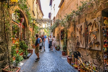 Visitors in a plant-covered lane with ancient buildings near the Cathedral of Orvieto (Duomo di Orvieto).