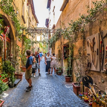 Visitors in a plant-covered lane with ancient buildings near the Cathedral of Orvieto (Duomo di Orvieto).