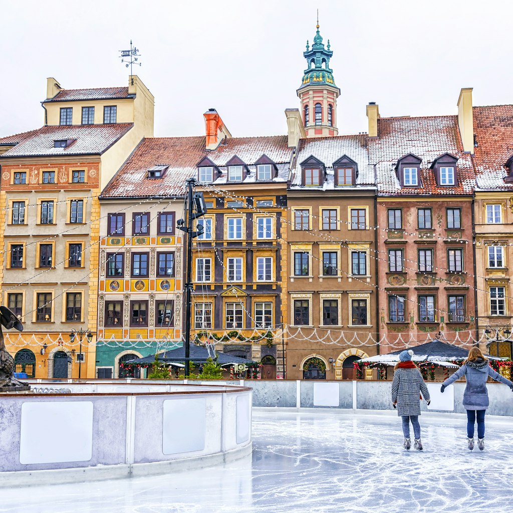 Two girls ice skate on a skating rink in the Old Town Square in Warsaw on Christmas eve.