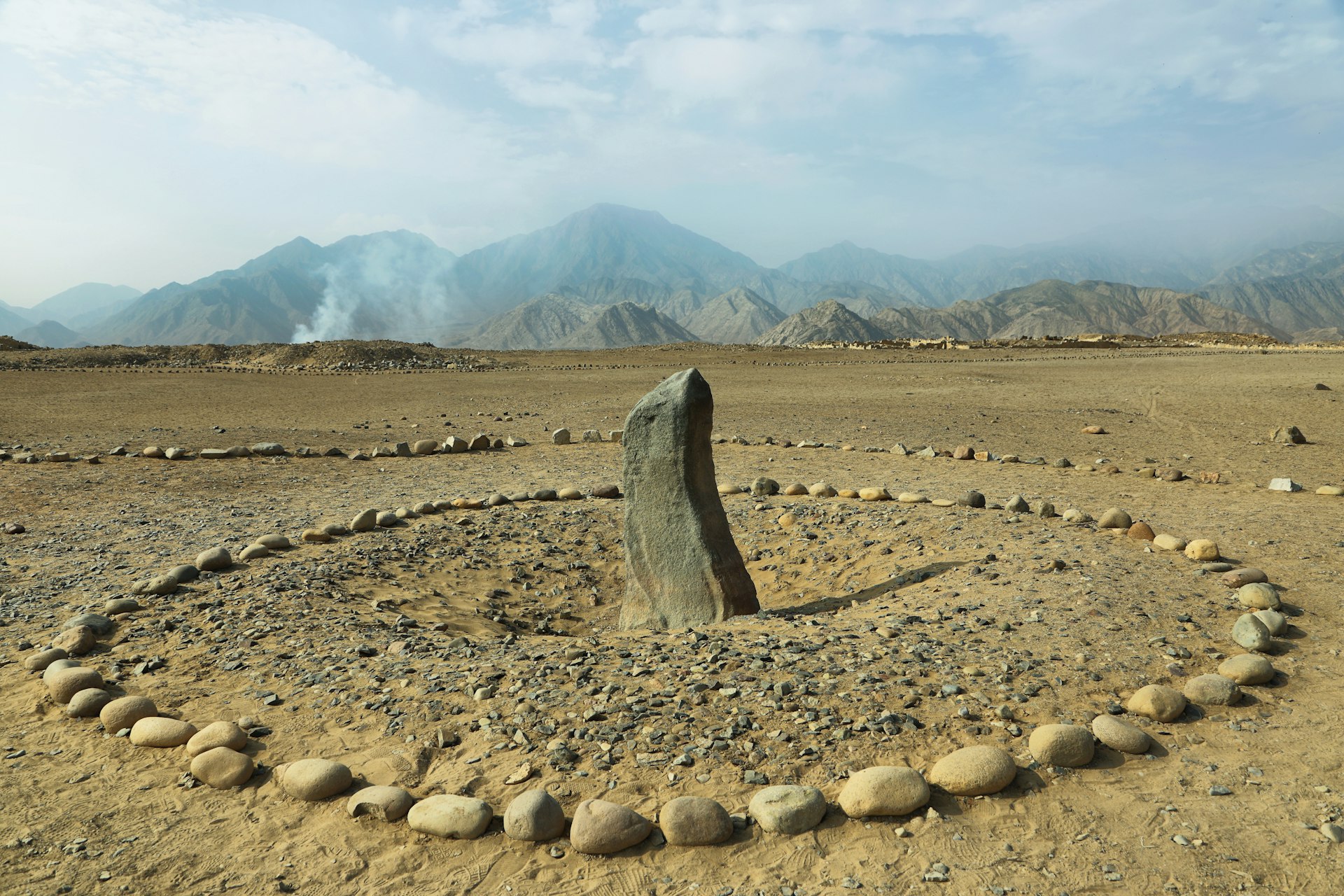 A circle of rocks sit in a barren desert. 