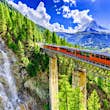 Gornergrat tourist train passing over the Findelbach Bridge with a waterfall and the Matterhorn in the background.