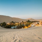 The sand dunes surrounding the small desert oasis of Huacachina at sunset.