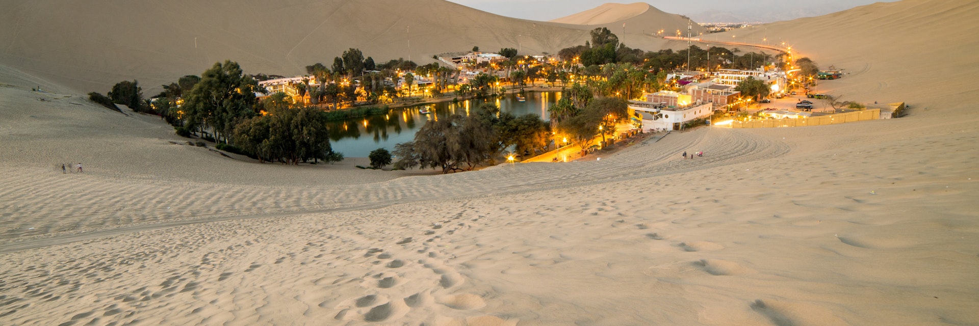The sand dunes surrounding the small desert oasis of Huacachina at sunset.