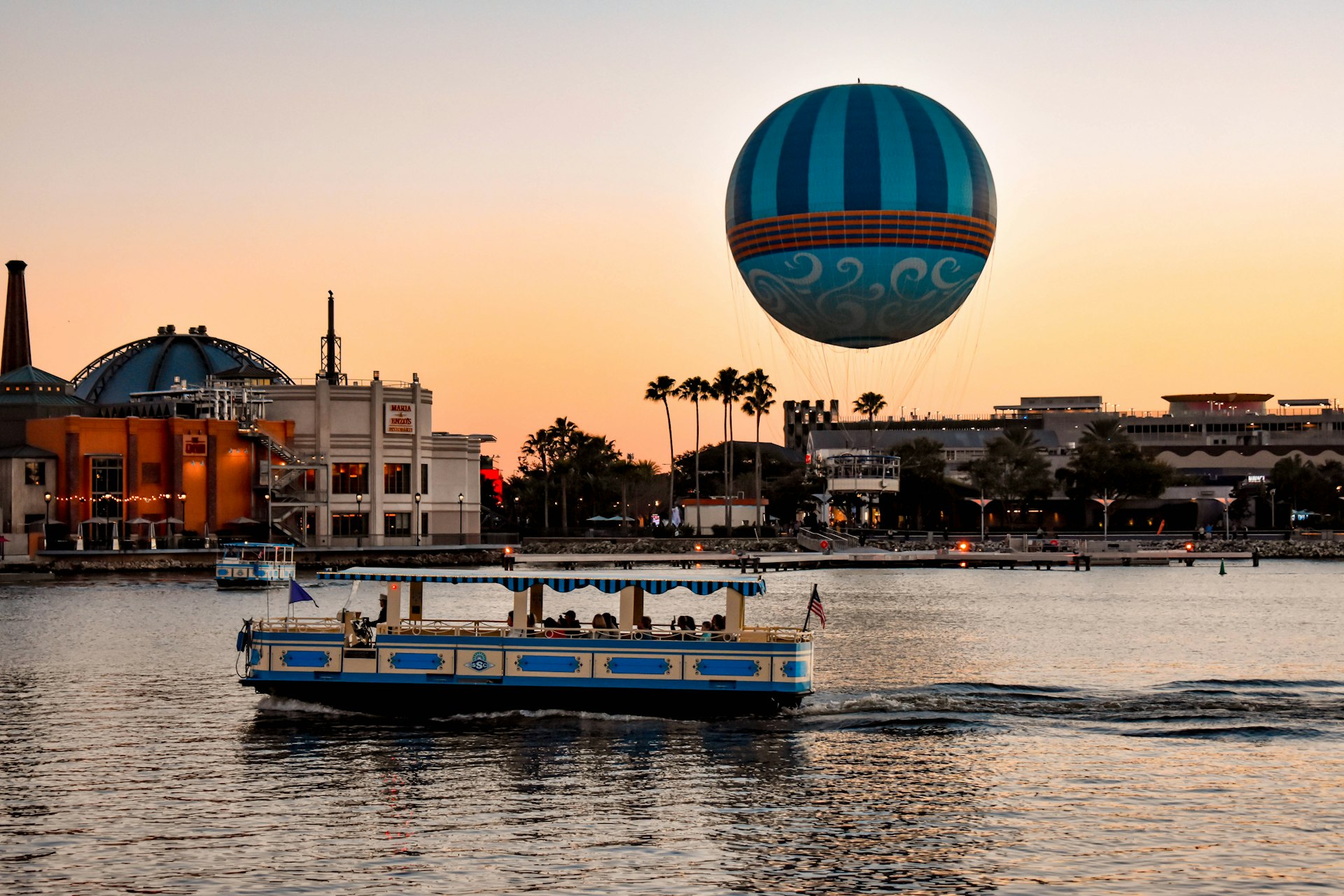 A water taxi passes by Disney Springs during sunset