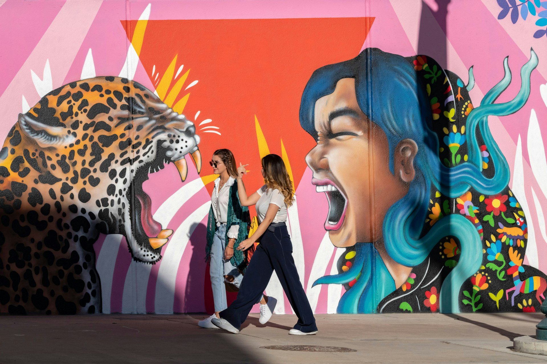 Girlfriends walk past a colorful mural in El Paso, Texas