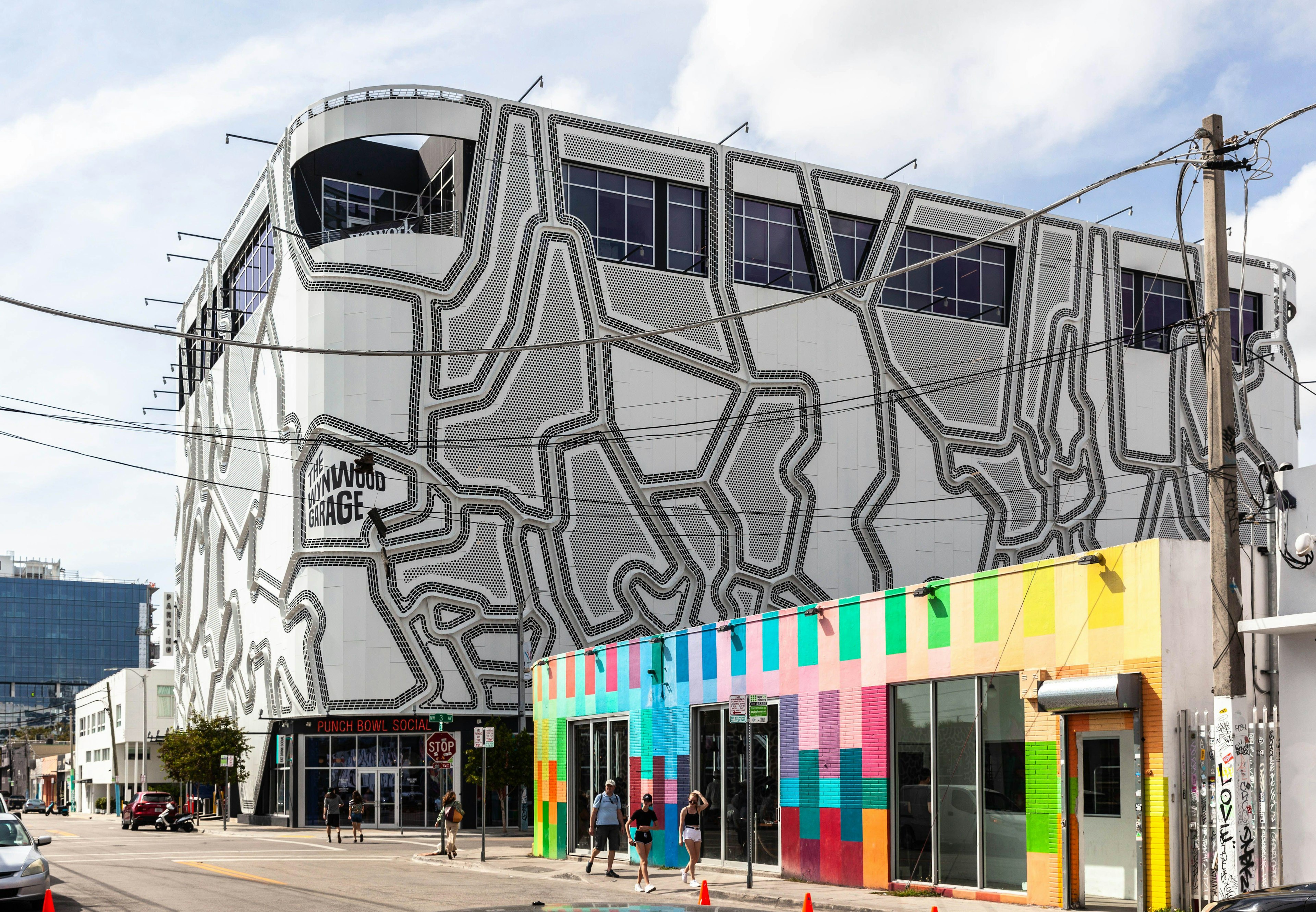 Exterior of a building with an unusual pattern of grey-and-white. Contrasting it is a nearby low-rise building with blocks of bright colors