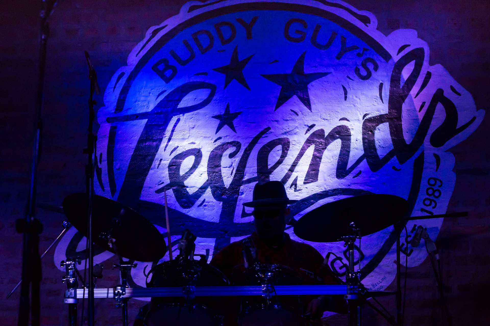 A drummer on stage at Buddy Guy's Legends jazz club in Chicago, Illinois, lit by blue lights.