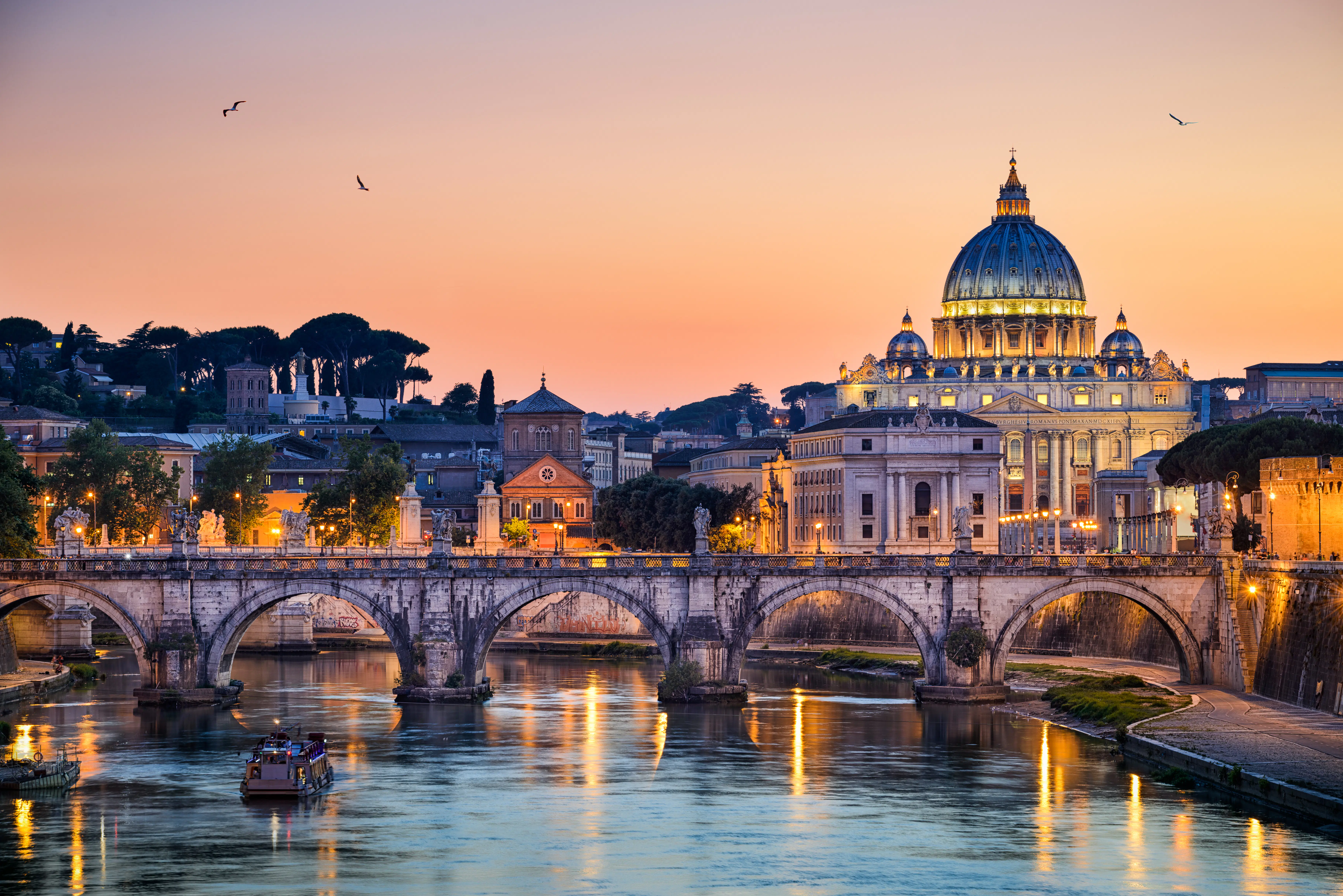 Con el antiguo puente Sant'Angelo y la Basílica de San Pedro del Vaticano alineados frente al cielo del atardecer.
