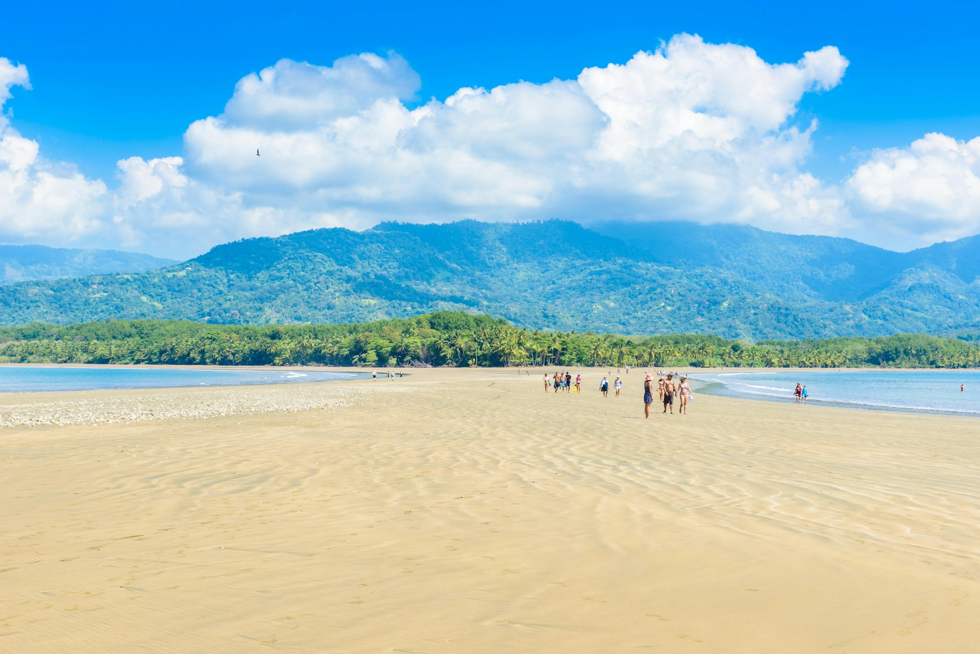 People walk over the expansive stretch of sand at Punta Uvita
