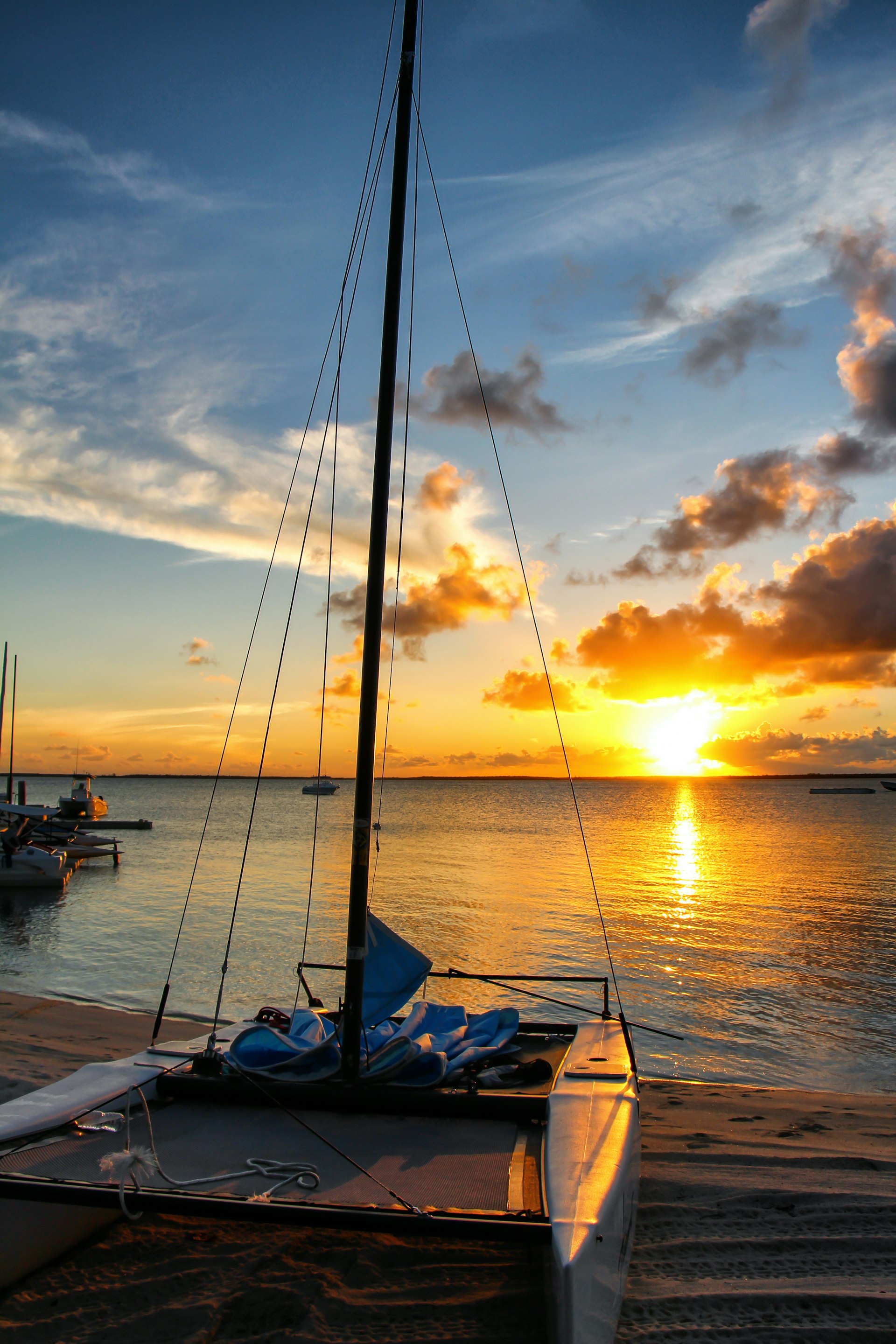 A boat rests on the sandy shore of a beach on Andros Island at sunset.  