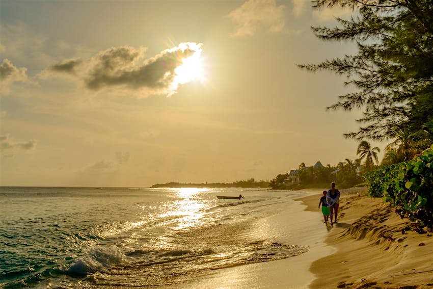 A couple strolls at sunset along the surf, sand and palm trees of Cemetery Beach, Cayman Islands.jpg
