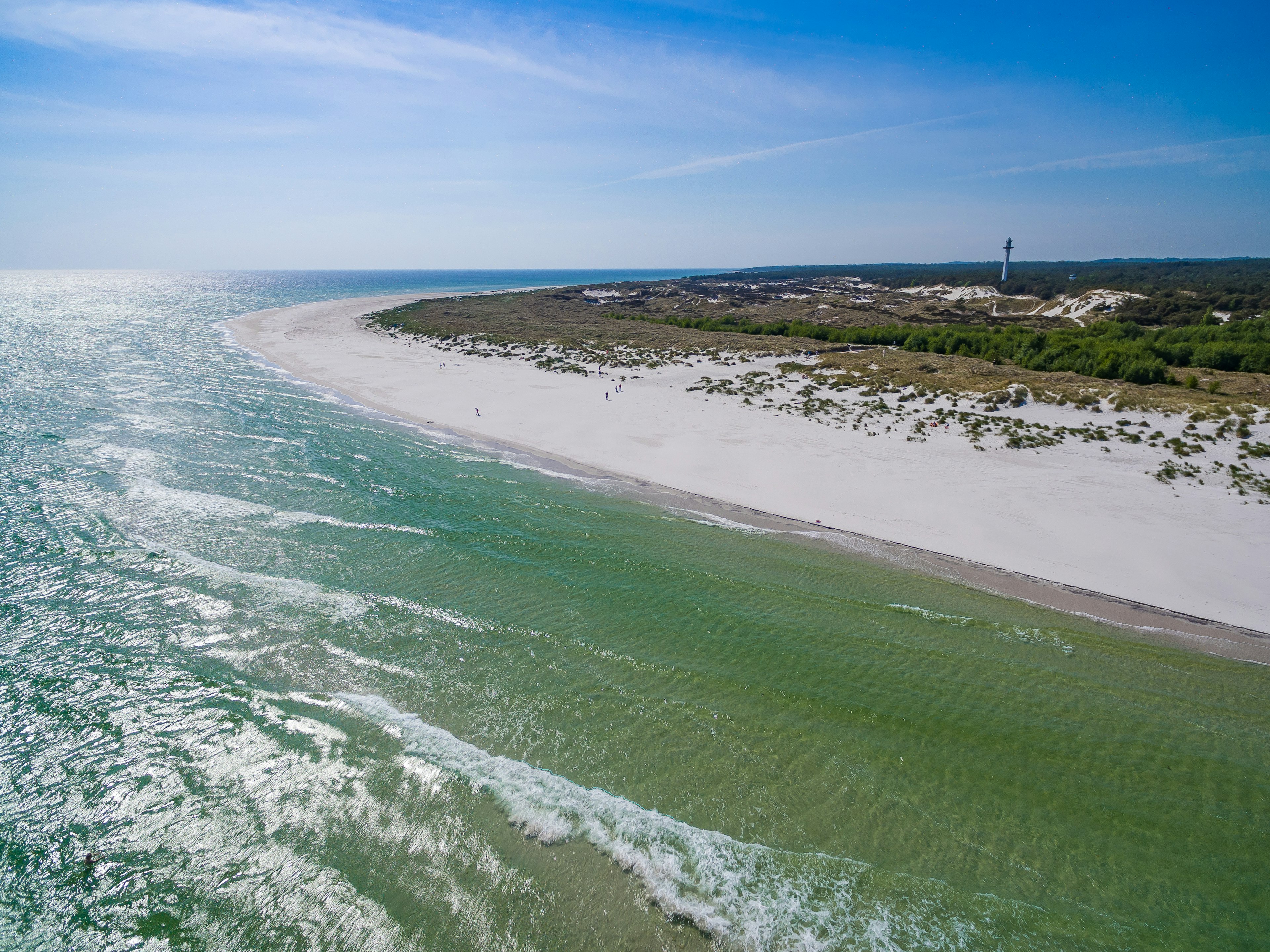 A vast white-sand beach curves around a headland and appears to stretch forever