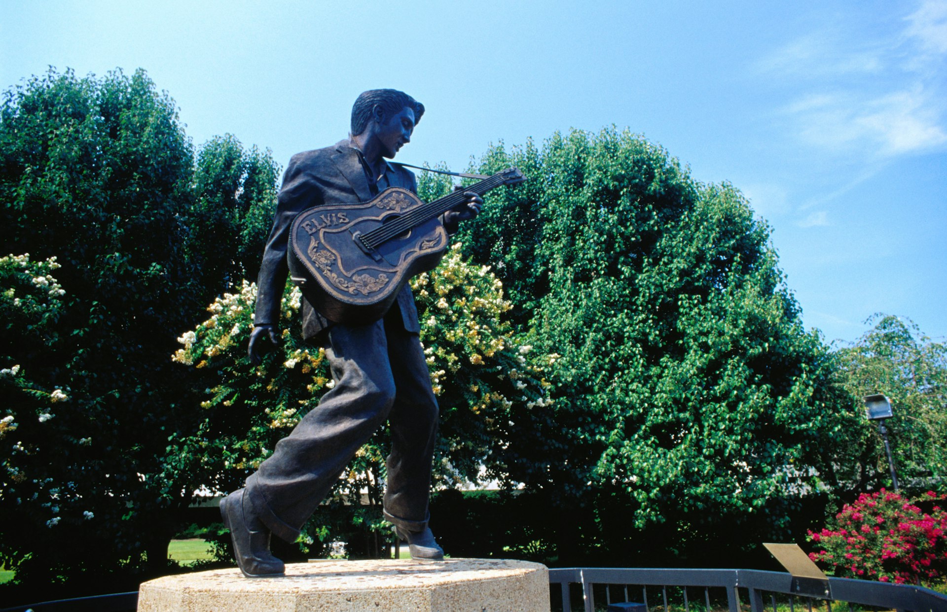 Statue of a man holding a guitar in parkland