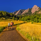 Hikers walking their dogs, The Flatirons rock formations, Chautauqua Park, Boulder, Colorado USA.