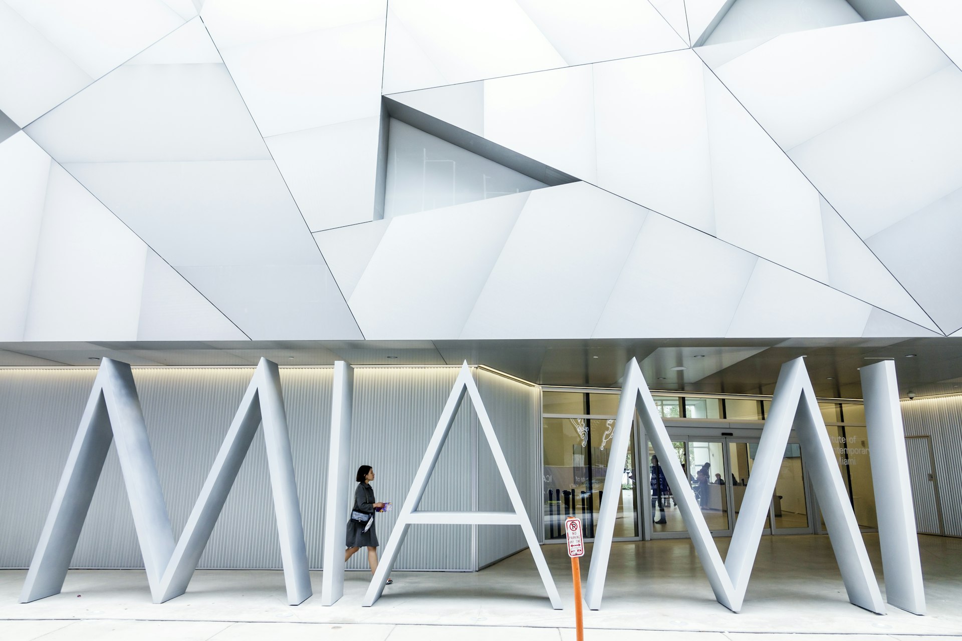 A woman walks past the white Institute of Contemporary Art in Miami entrance, which spells out Miami in the architecture