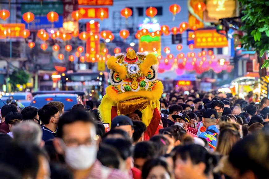 A dancer carries a dragon head on the crowded main street in Bangkok Chinatown on the first day of the Lunar New Year