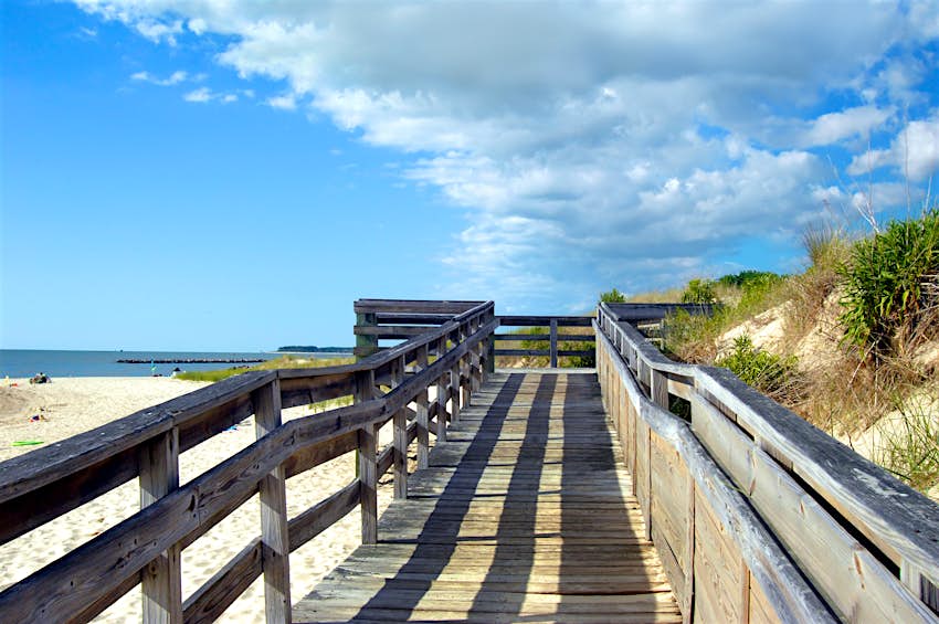 A boardwalk over coastal sand dunes, with blue skies above