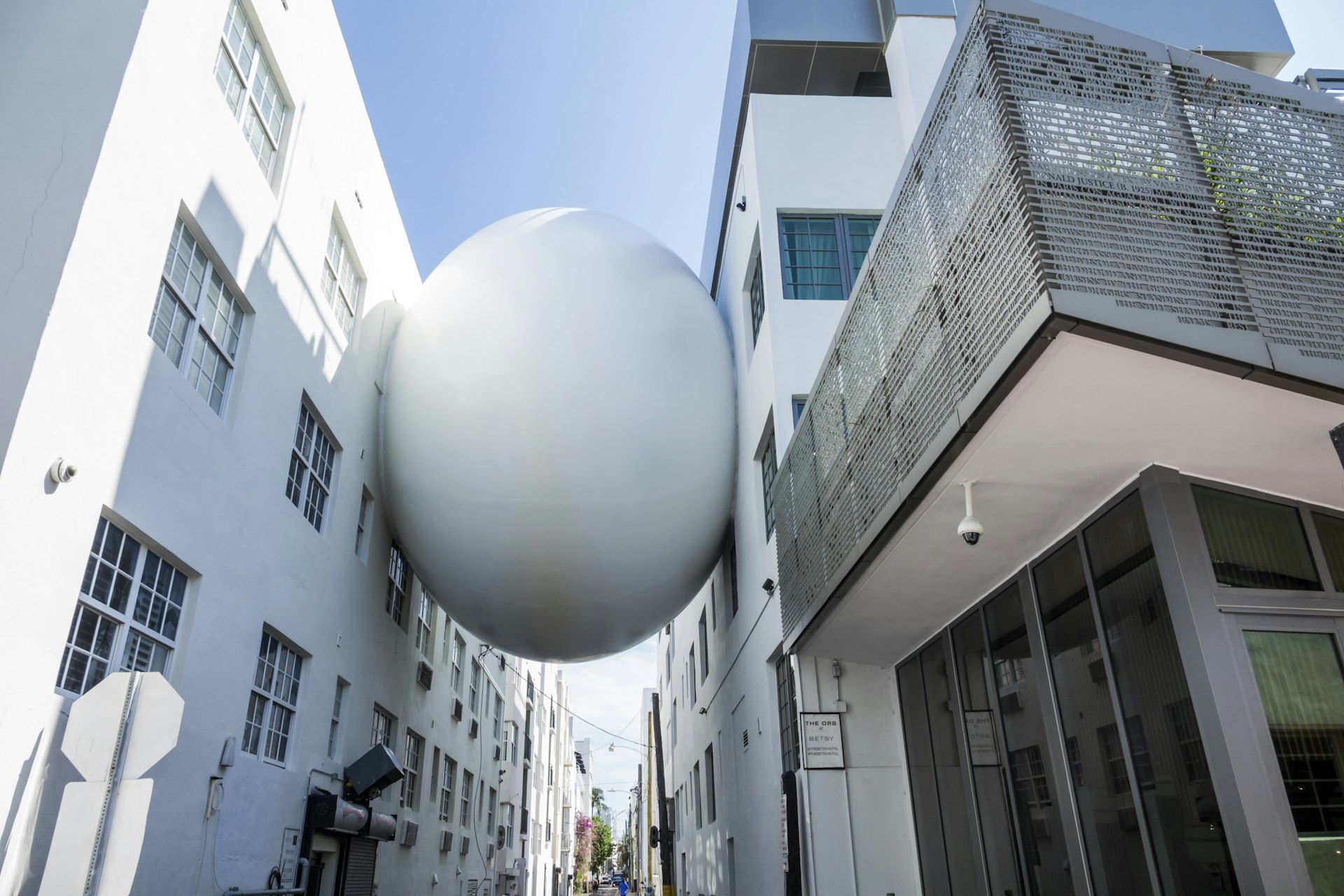 The Orb artwork, a large white sphere, sits squashed between the Betsy Hotel and the building next door