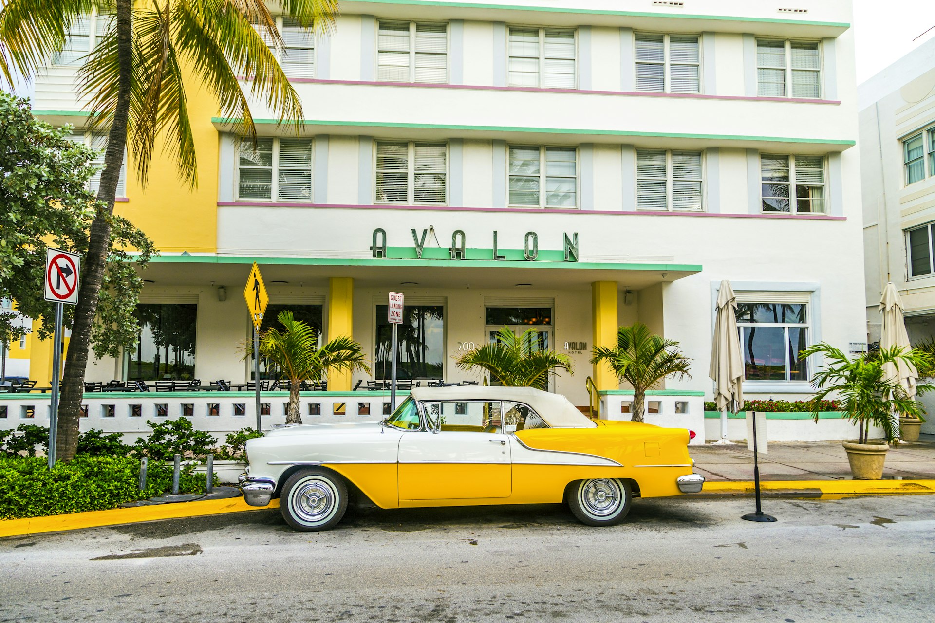 Classic car with chrome radiator grill parks in front of the art deco restaurant and Hotel Avalon in Miami Beach, Florida