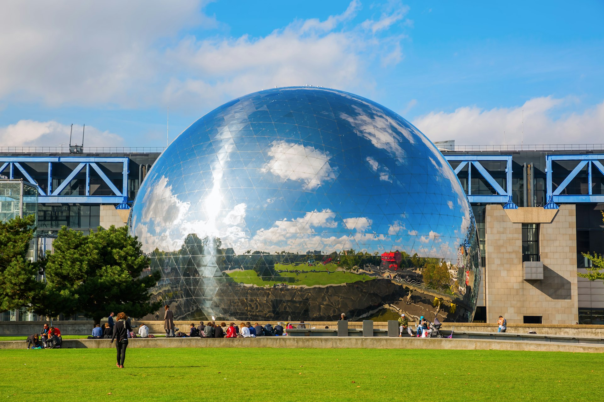 A mirror-finished geodesic dome sits in a lush, green park. 