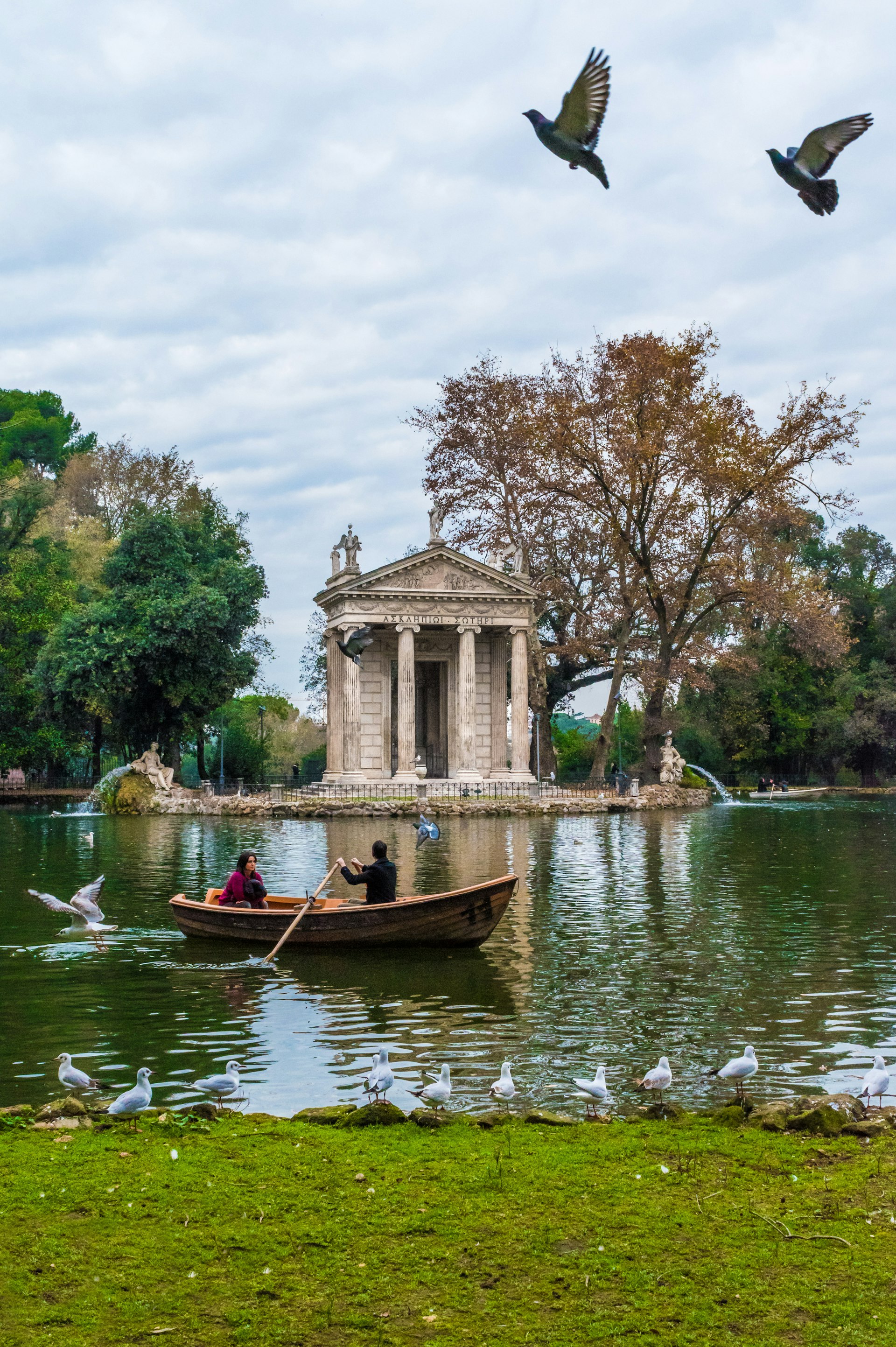 Two people enjoy a canoe ride on a lake in Villa Borghese park. 