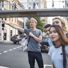 Young man hailing taxi while standing with friends on a Sydney street.