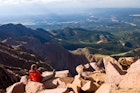 "Vista Scenic View from Pikes Peak Summit Colorado.  Hiker enjoying scenic view on beautiful, sunny day.  Young athletic man kicking back on warm sunny rocks.  Legs outstretched in front.  Captured as a 14-bit Raw file. Edited in ProPhoto RGB color space."