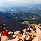 "Vista Scenic View from Pikes Peak Summit Colorado.  Hiker enjoying scenic view on beautiful, sunny day.  Young athletic man kicking back on warm sunny rocks.  Legs outstretched in front.  Captured as a 14-bit Raw file. Edited in ProPhoto RGB color space."