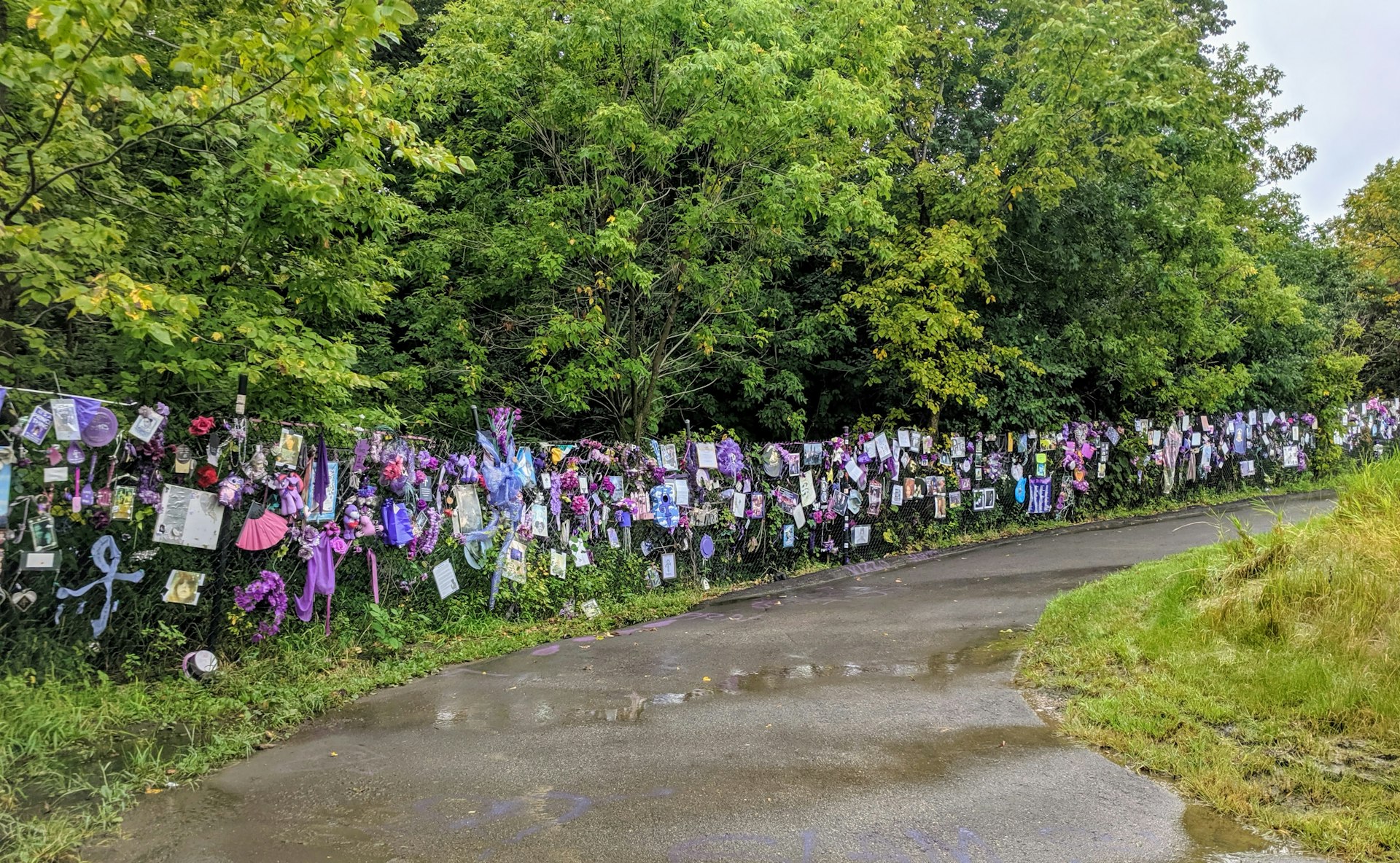 A chainlink fence is lined with purple memorabilia and other tributes to the musician Prince near Paisley Park in Minneapolis, Minnesota