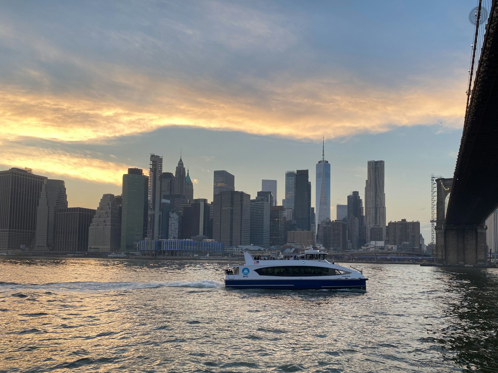 A NYC ferry in the East River, passing under the Brooklyn Bridge