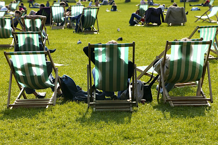 Hyde Park deck chairs People lounge in green-and-white striped deck chairs shot from behind in a park on a sunny day