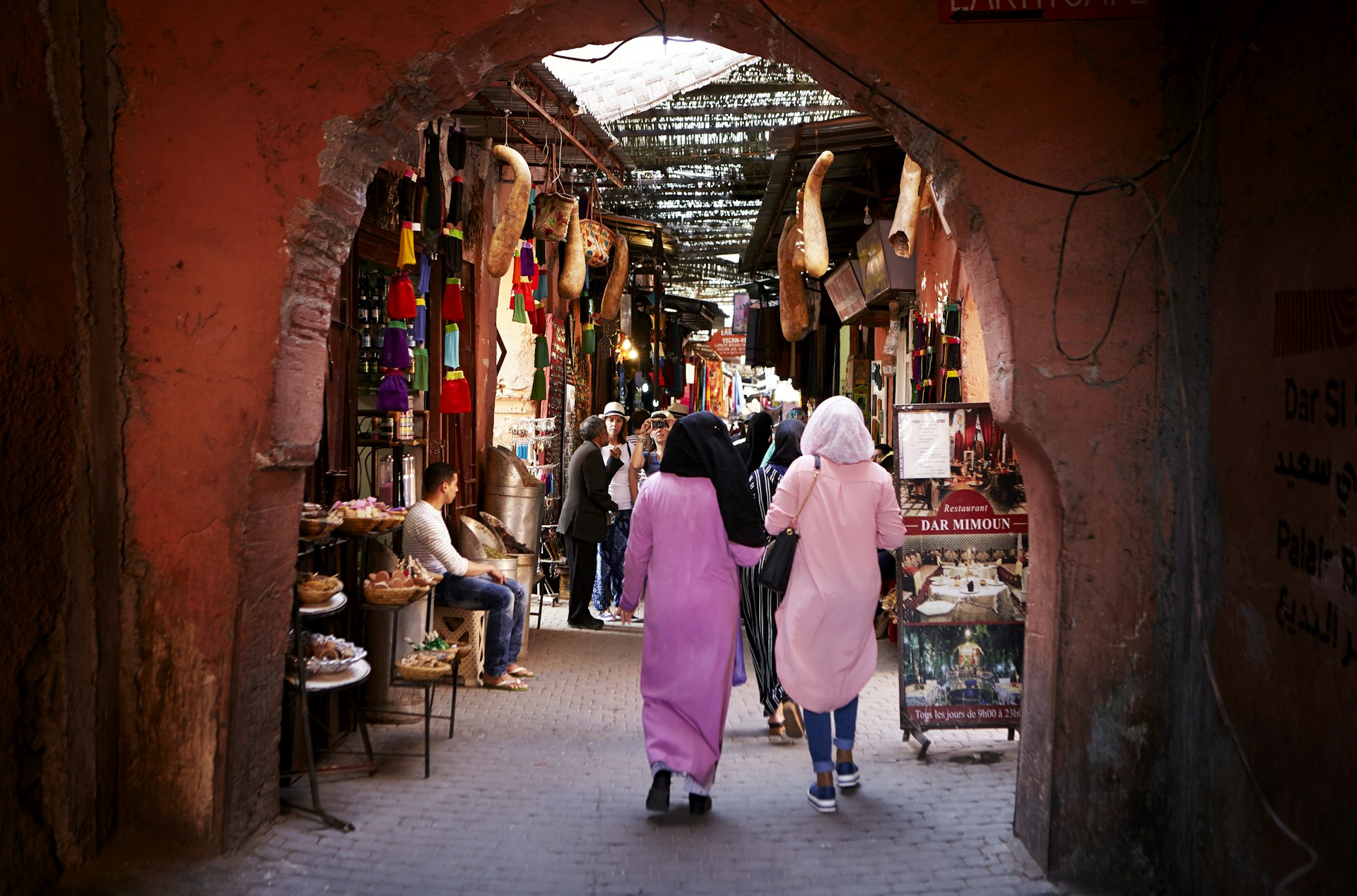 People walk through a stone arch in a medina