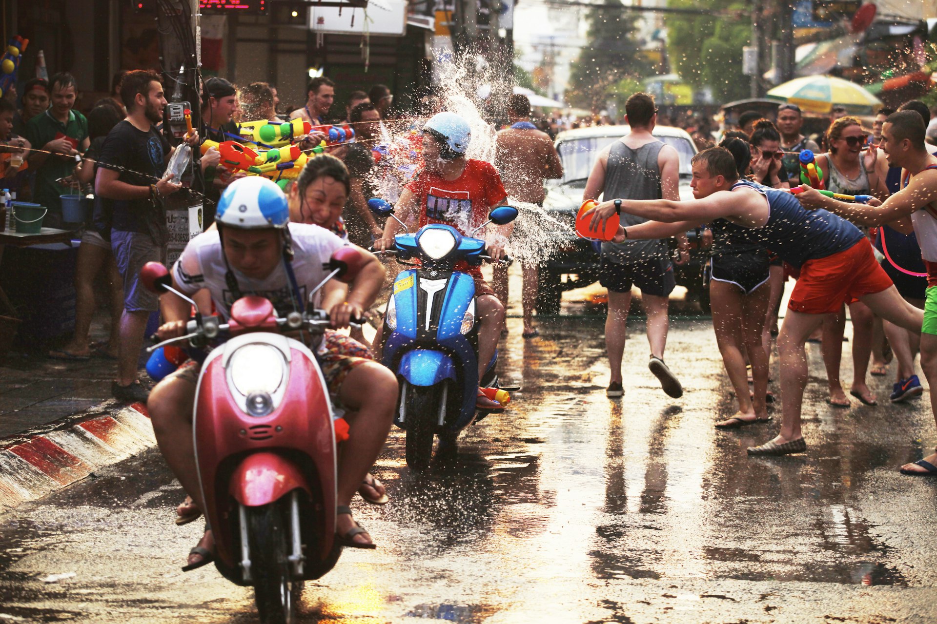 Motorbikes and riders being soaked with water during the Songkran Festival. 